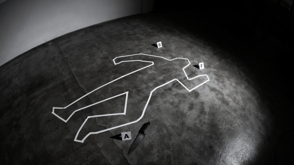 A crime scene outline on a concrete floor with white tape marking the silhouette of a human body.